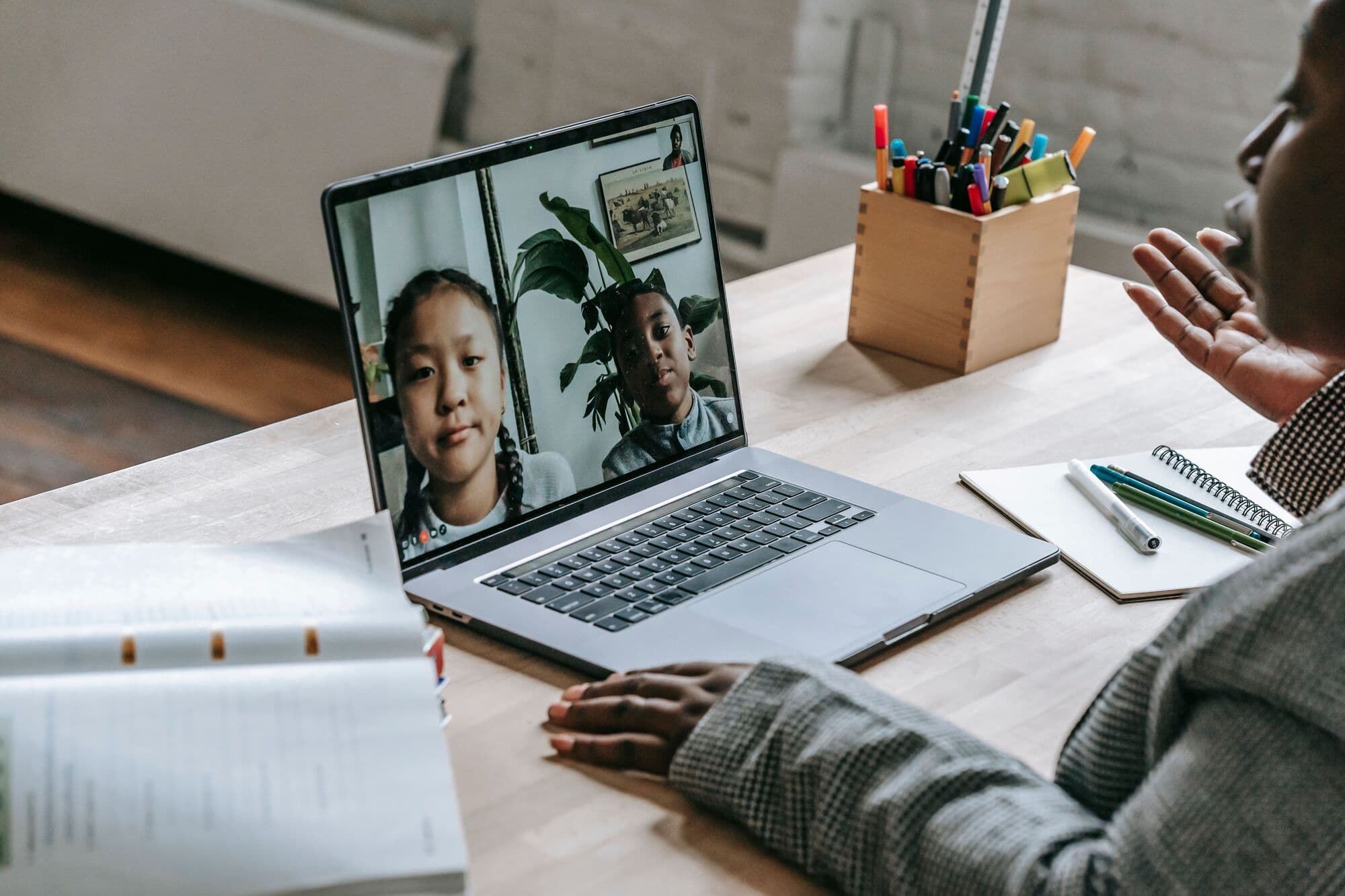 A tutor greets two learners on a group video call
